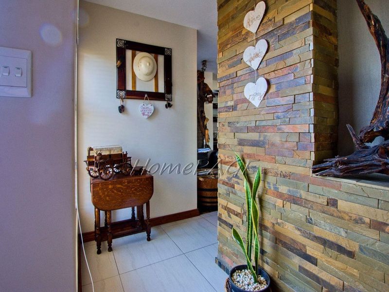 A bright hallway featuring a textured stacked stone accent wall and neutral tiled flooring, creating a warm and inviting entrance to the home.
