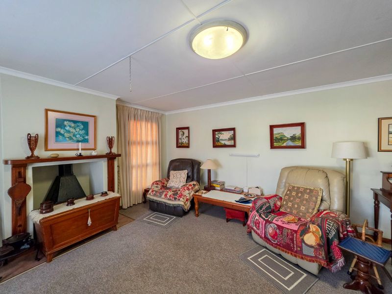 A cozy living room featuring a traditional fireplace with a wooden mantelpiece, carpeted flooring, and neutral wall finishes.