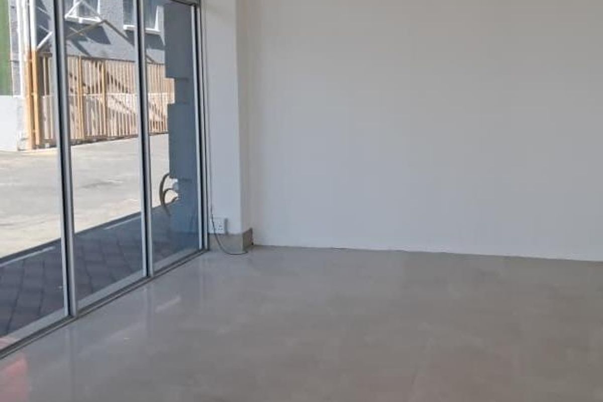 A bright, empty open-plan retail space featuring large glass storefront windows and clean tiled flooring, suitable for various commercial business applications.