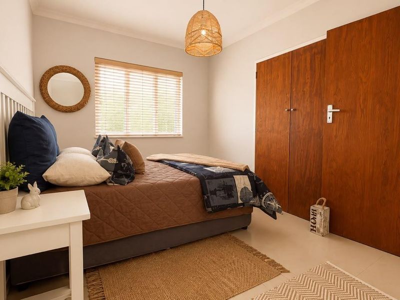 A well-maintained bedroom featuring neutral walls, tiled flooring, and built-in wooden cupboards, offering a clean and functional living space.