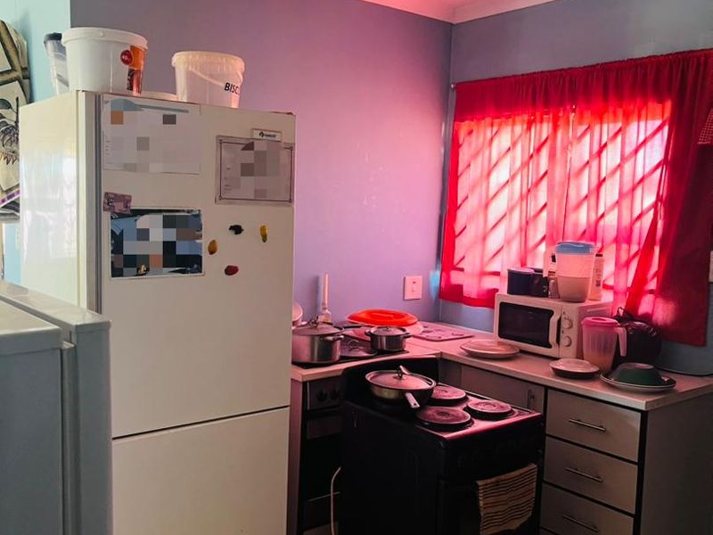 A compact kitchen featuring tiled flooring, built-in cabinetry, and a freestanding stove, currently requiring cosmetic updates to modernize the space.