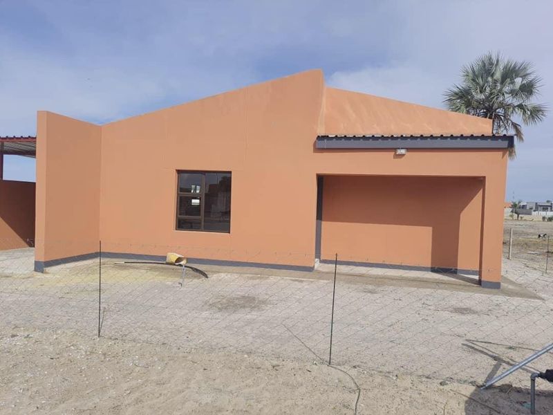 Front elevation of a modern single-story house featuring a paved driveway, covered entrance, and neutral exterior wall finish.