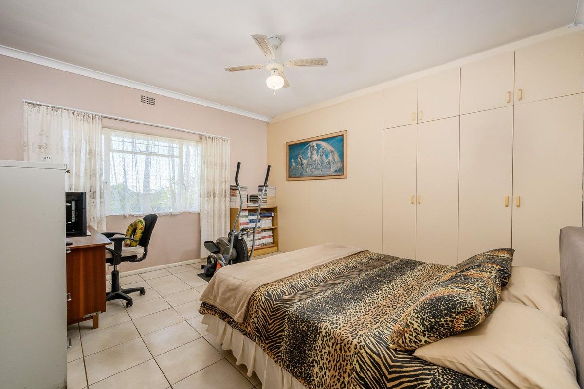 A functional bedroom featuring built-in floor-to-ceiling cabinetry, tiled flooring, and a ceiling fan, offering a practical layout for comfortable living.