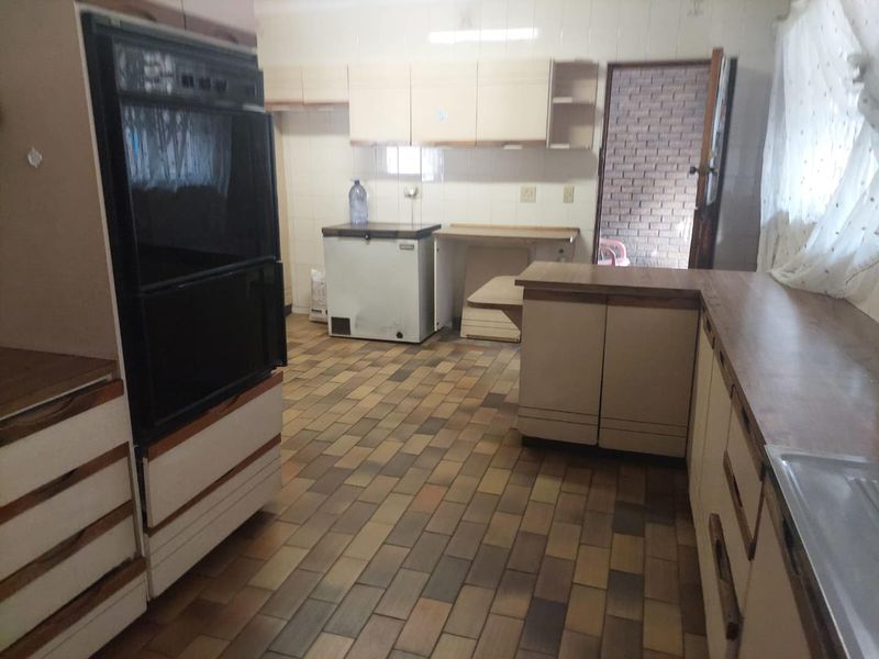 A dated kitchen featuring built-in cabinetry, laminate countertops, and tiled flooring, offering significant potential for modernization and renovation.