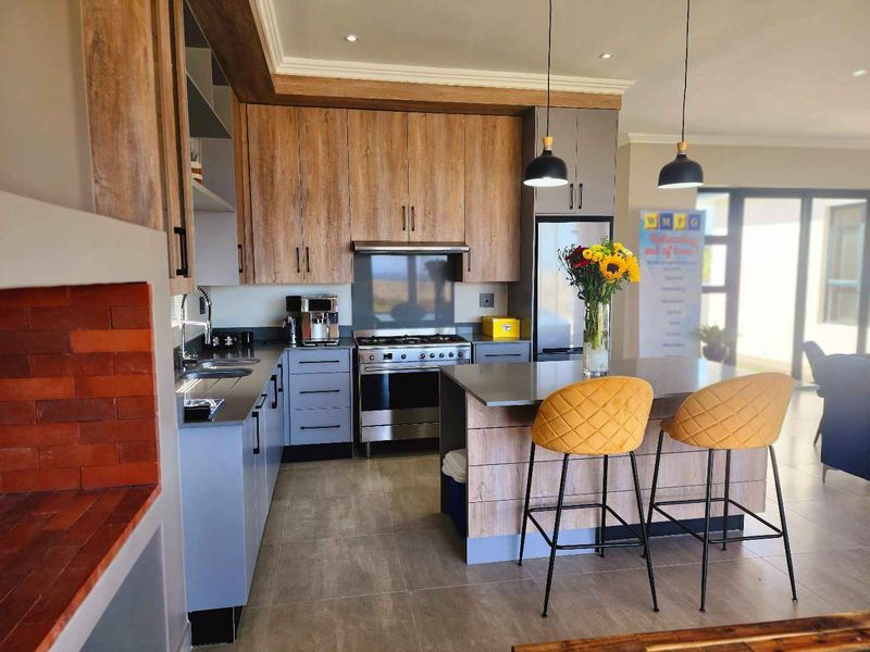 Modern kitchen featuring wood-look and grey cabinetry, a central island with breakfast bar, gas stove, and sleek tiled flooring in an open-plan layout.