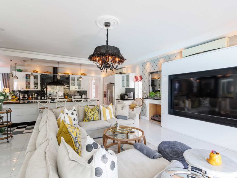 Spacious open-plan living area featuring a modern kitchen with island, built-in fireplace, and elegant ceiling details, creating a cohesive and functional living space.