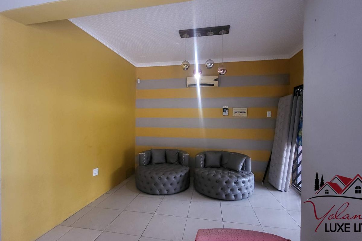 A living room area featuring tiled flooring, coved ceilings, and a wall-mounted air conditioning unit.