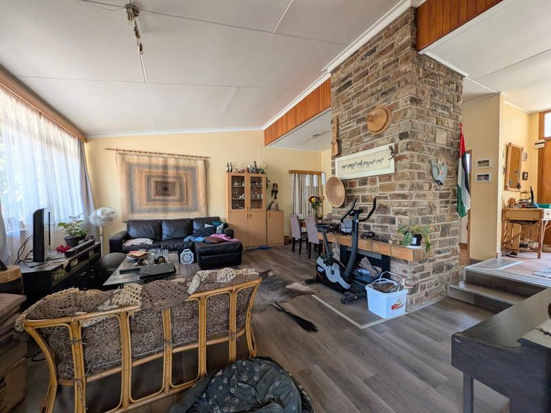 Open-plan living and dining area featuring a prominent brick fireplace, laminate flooring, and direct access to adjacent living spaces.