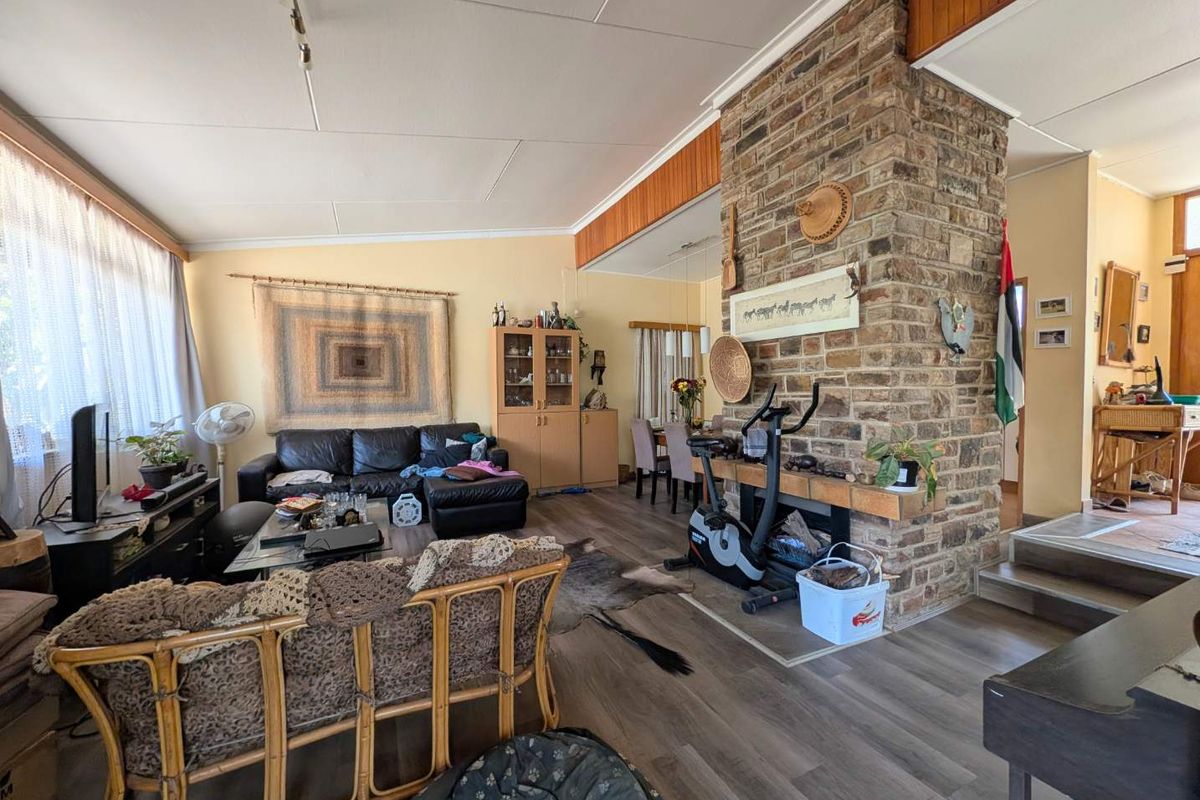 Open-plan living and dining area featuring a prominent brick fireplace, laminate flooring, and direct access to adjacent living spaces.