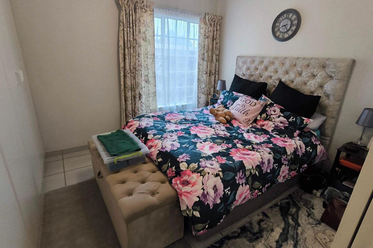 A bedroom featuring tiled flooring and a built-in wardrobe, offering a functional space with natural light from the window.