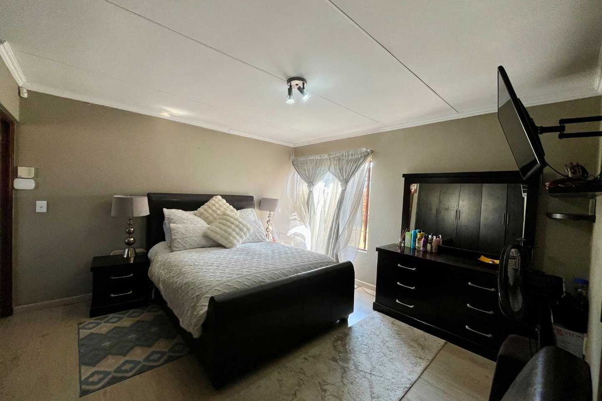 A well-proportioned bedroom featuring neutral wall tones, tiled flooring, and classic ceiling cornicing, providing a comfortable and functional living space.