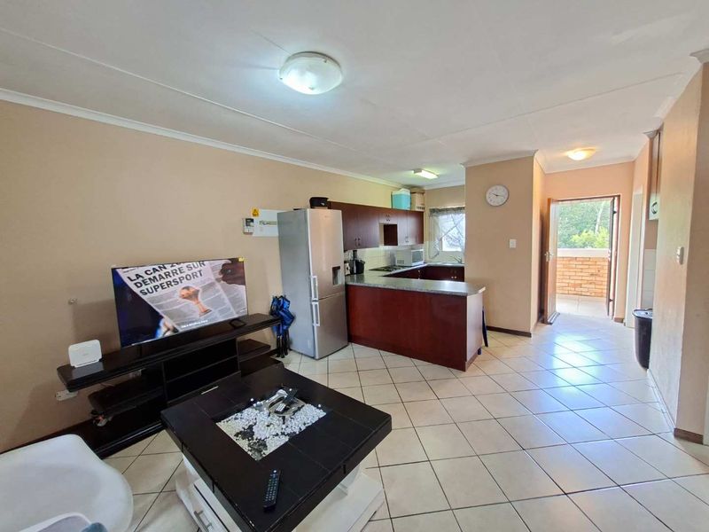 Open plan living area featuring tiled floors and a functional kitchen with built-in cabinetry, providing direct access to an outdoor balcony space.