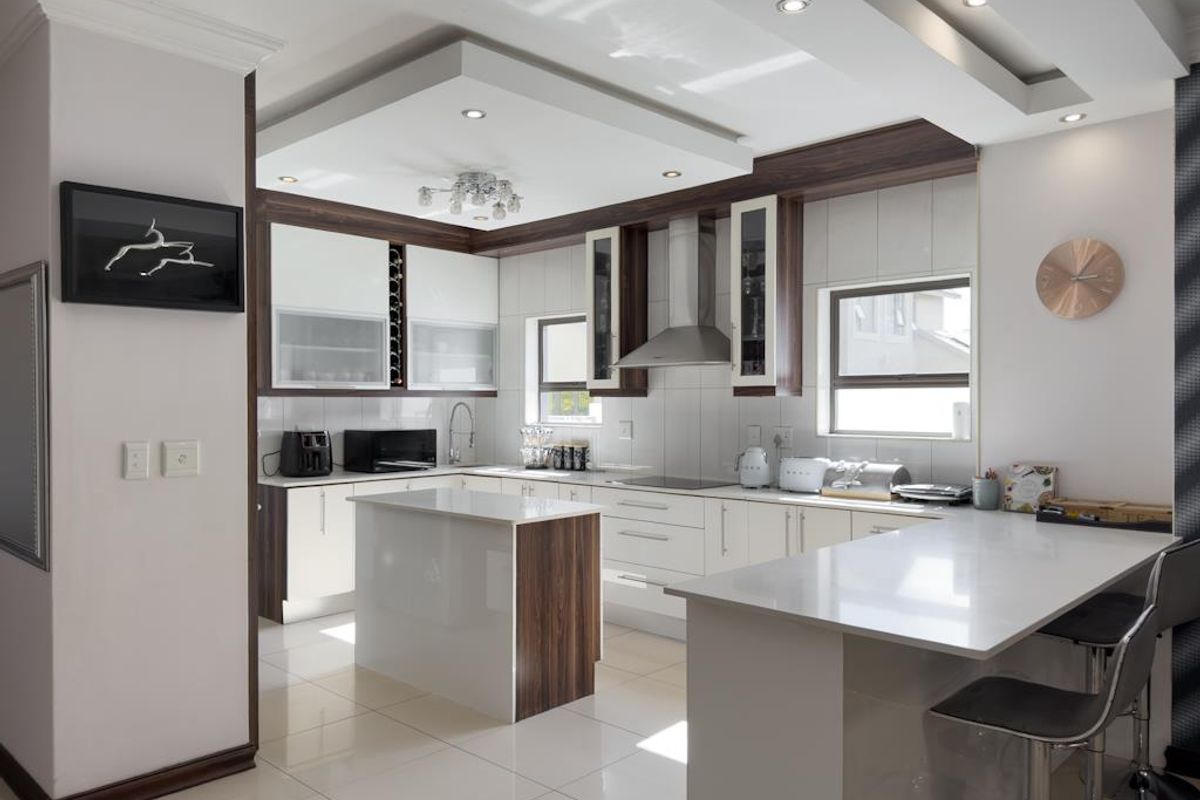 Modern kitchen featuring high-gloss cabinetry, stone countertops, a central island, integrated extractor fan, and recessed ceiling lighting.