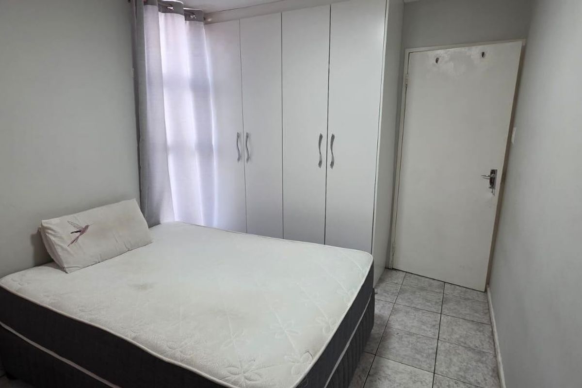 A functional bedroom featuring built-in cupboards and tiled flooring, providing a clean and practical living space.