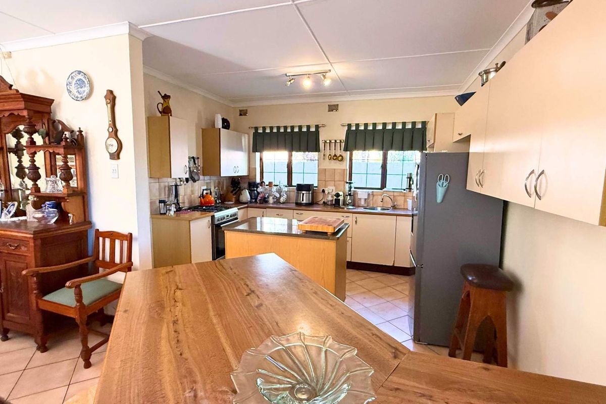 A functional kitchen featuring built-in cabinetry, a central island, tiled flooring, and a tiled backsplash, offering a practical layout for daily meal preparation.