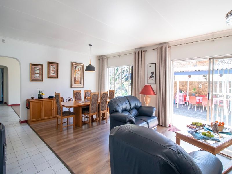 Open-plan living and dining area featuring laminate flooring, tiled transition space, and sliding glass doors providing direct access to the rear patio.