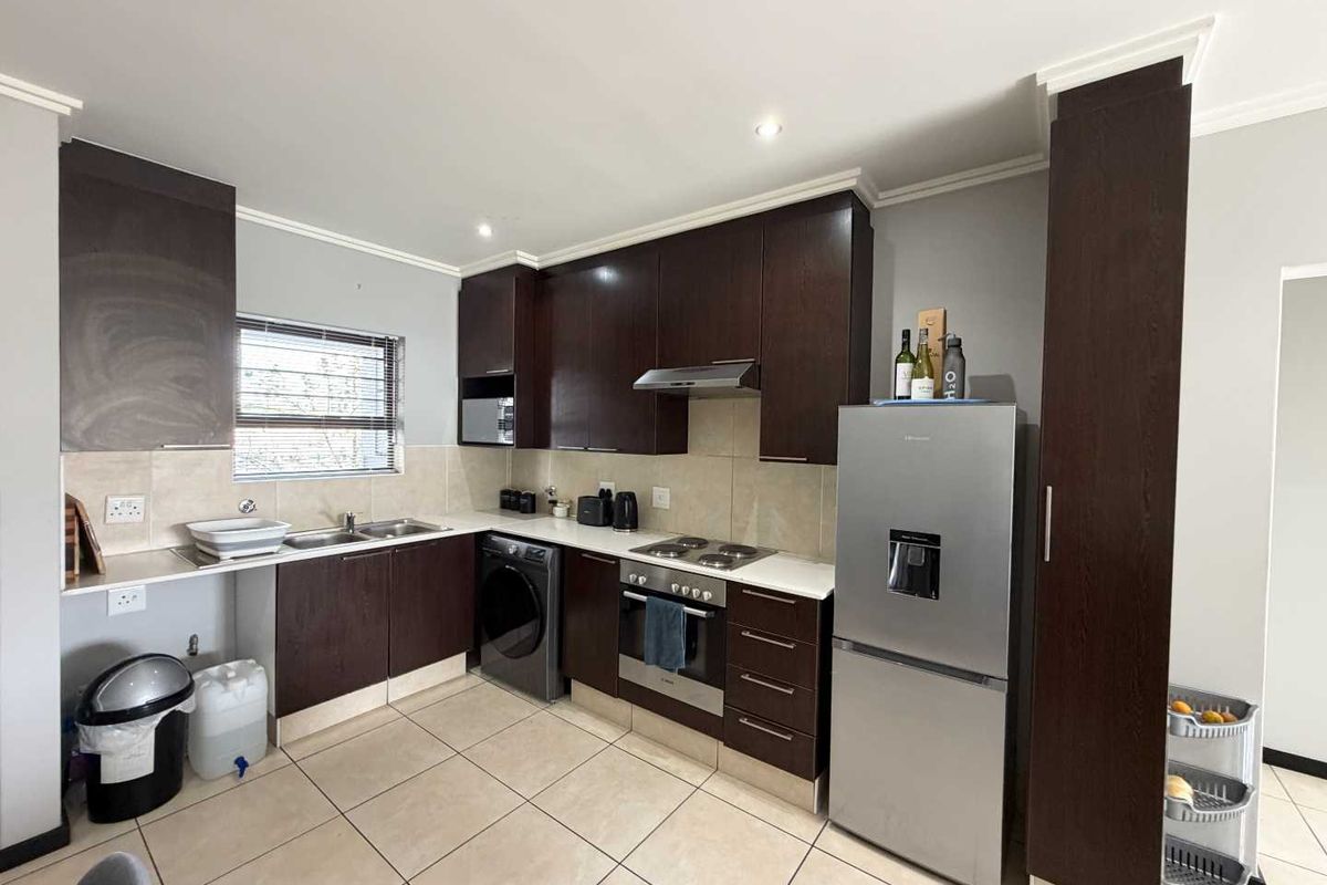 A functional kitchen featuring dark wood cabinetry, stainless steel appliances, tiled backsplash, and tiled flooring, offering a clean and practical workspace.