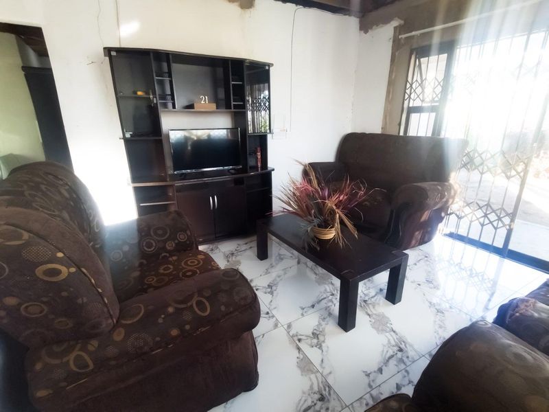 Living room featuring marble-look floor tiles and security gate access, currently requiring plaster and ceiling finishing to complete the space.