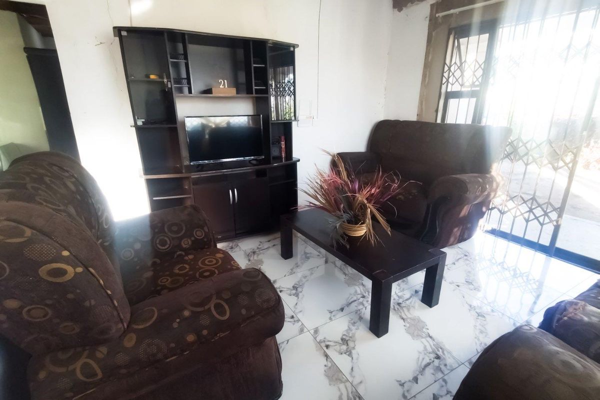 Living room featuring marble-look floor tiles and security gate access, currently requiring plaster and ceiling finishing to complete the space.