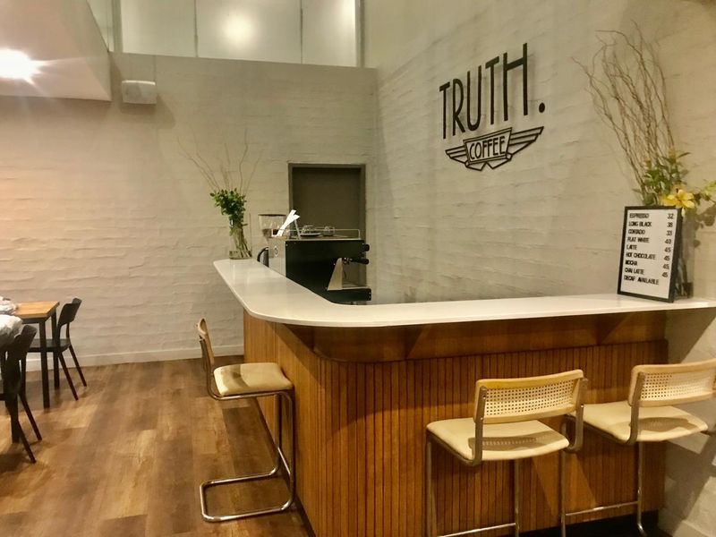 A commercial-style bar area featuring a built-in counter with timber paneling, a clean laminate top, and warm timber flooring.