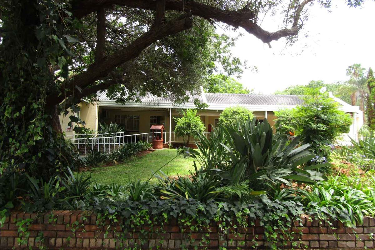 A view of the retirement village unit featuring a covered patio, established garden, and mature trees, providing a peaceful outdoor setting.