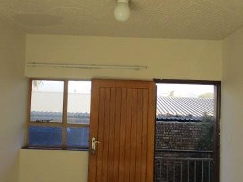 An empty bedroom featuring tiled flooring, a timber door, and direct access to a small balcony area.