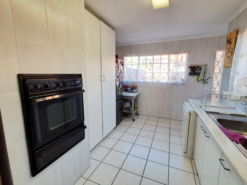 A functional kitchen featuring built-in oven, tiled surfaces, and ample cabinetry, offering a dated layout ready for modern renovation and aesthetic updates.