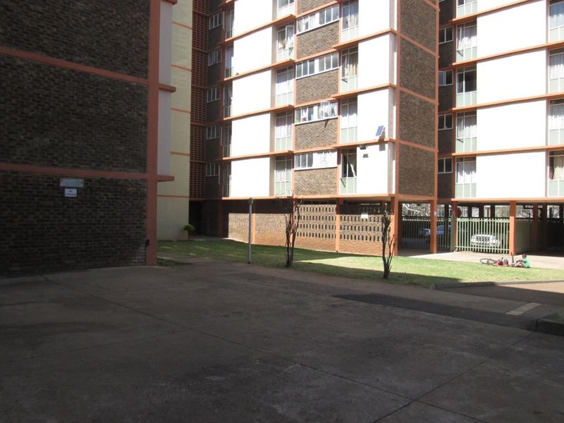 Exterior view of an apartment complex featuring brick facades, concrete paved areas, and a shared lawn space.