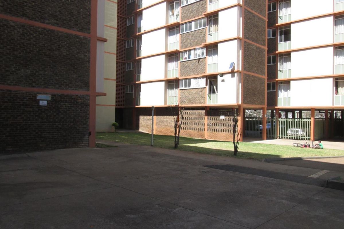 Exterior view of an apartment complex featuring brick facades, concrete paved areas, and a shared lawn space.