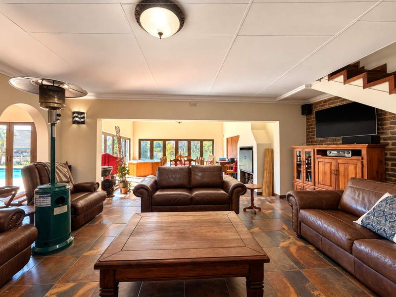 Spacious open-plan living area featuring tiled floors, an exposed brick feature wall, a built-in fireplace, and direct access to the outdoor patio and pool area.