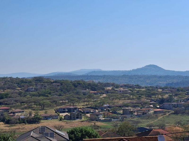 A scenic elevated view overlooking a residential neighborhood with rolling hills and mountains in the background.