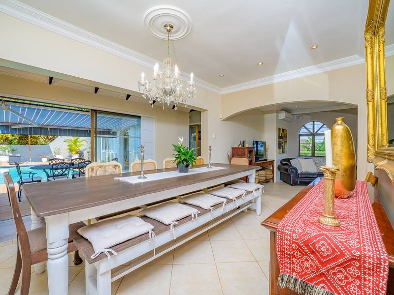 Spacious open-plan dining area featuring elegant ceiling roses, recessed lighting, and large sliding doors providing seamless access to the outdoor pool area.