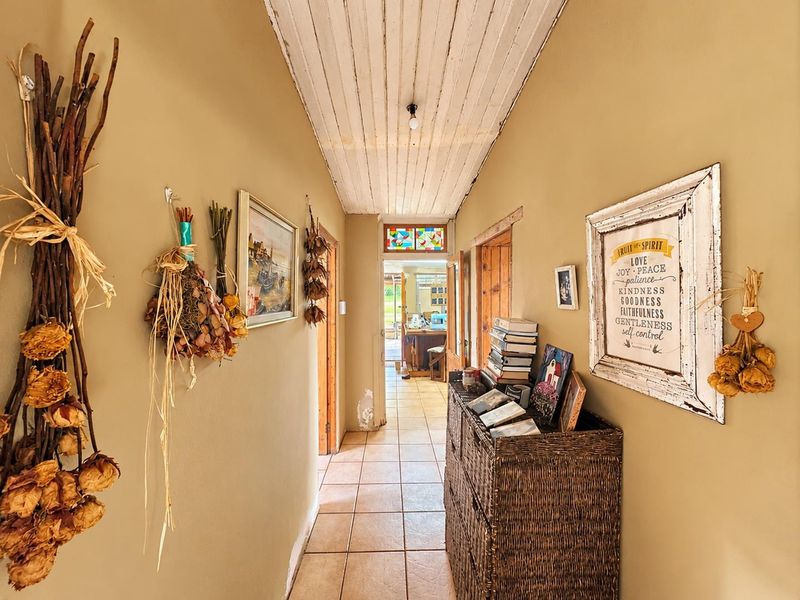 A narrow hallway featuring tiled flooring, a timber panelled ceiling, and a decorative stained glass transom window above the doorway.