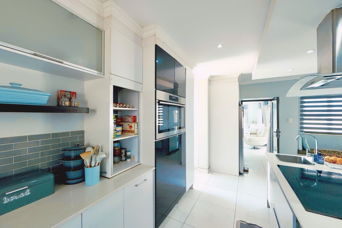 Modern kitchen featuring sleek fitted cabinetry, built-in oven and microwave, stainless steel sink, and a stylish subway tile backsplash with tiled flooring.