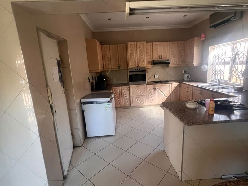 A functional kitchen featuring built-in cabinetry, granite countertops, integrated oven, and tiled flooring, offering a practical layout with ample storage space.