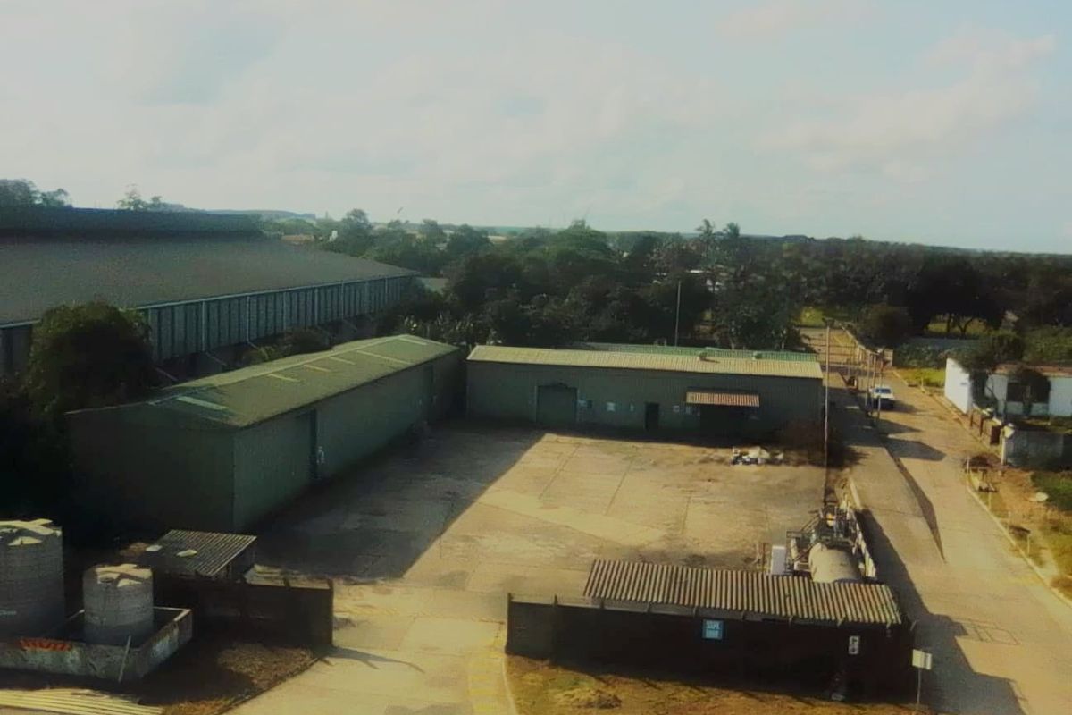 Aerial view of an industrial property featuring multiple warehouse structures, a paved yard area, and perimeter fencing.