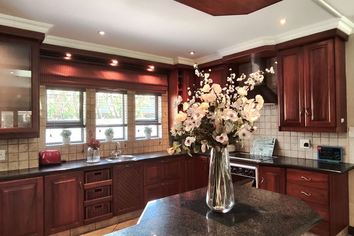 A well-maintained kitchen featuring dark wood cabinetry, granite countertops, a tiled backsplash, and integrated appliances with recessed lighting.