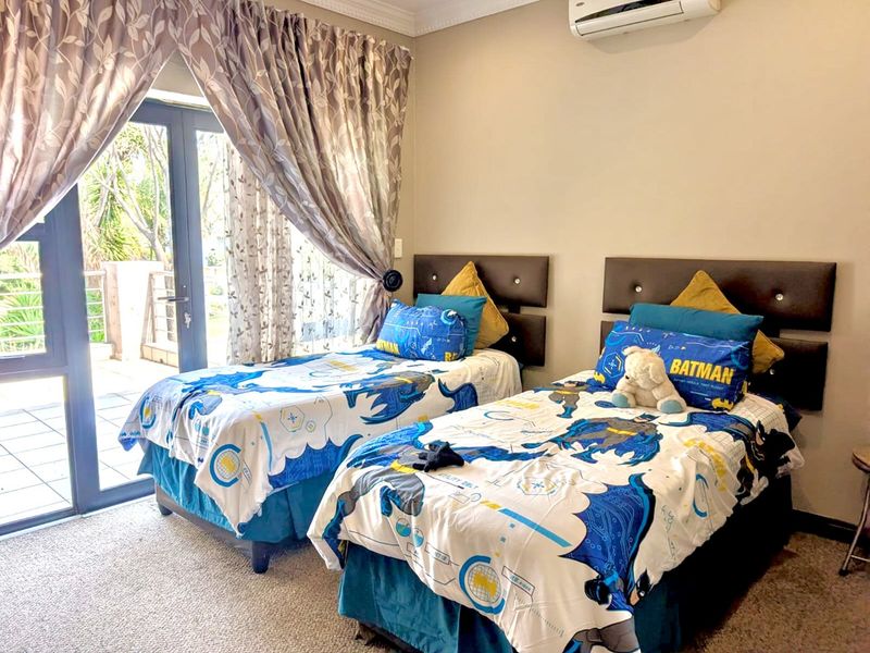 A well-maintained bedroom featuring carpeted flooring, a wall-mounted air conditioning unit, and a sliding glass door providing access to an outdoor area.