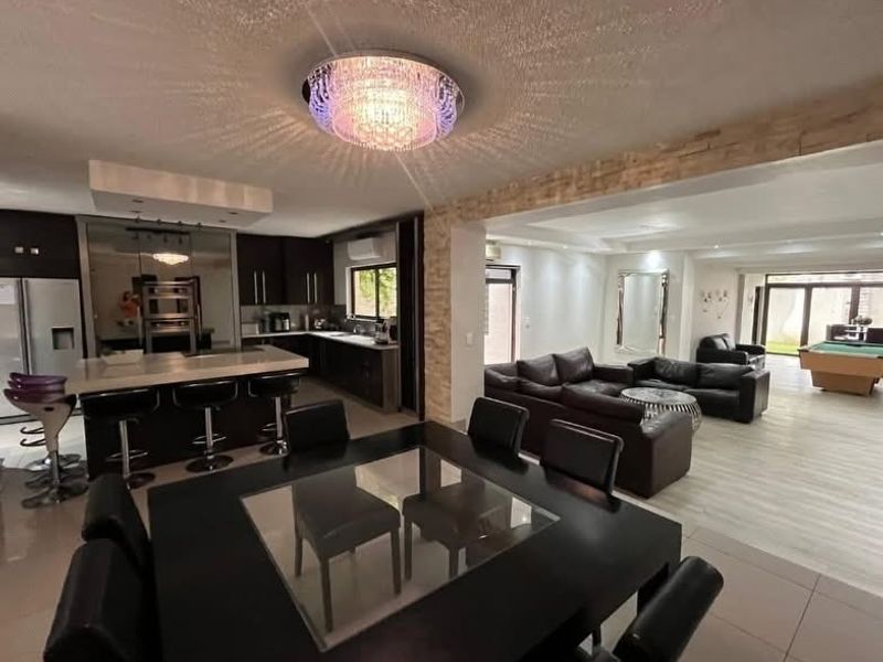 Spacious open-plan living area featuring a modern kitchen with island, dining space, and lounge area with stone feature wall and contemporary lighting.