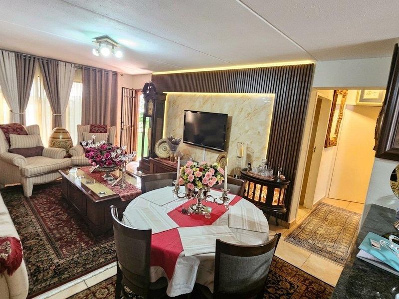 Spacious open-plan living and dining area featuring a modern slatted wood feature wall with integrated lighting and marble-look paneling.