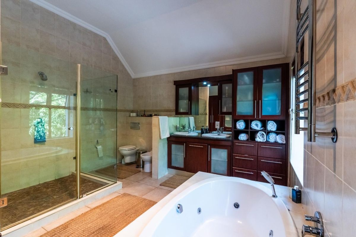 Spacious bathroom featuring a large corner jetted tub, glass-enclosed shower, dual vanity with dark wood cabinetry, and a heated towel rail.