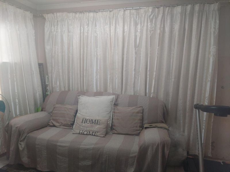 A living room area featuring full-length window curtains and neutral wall finishes.
