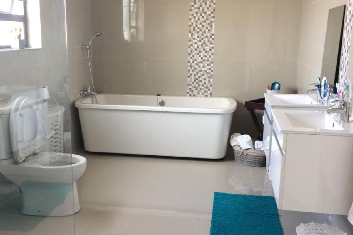 Modern bathroom featuring a freestanding bathtub, double vanity with integrated sinks, and a glass-enclosed shower area with neutral wall and floor tiling.