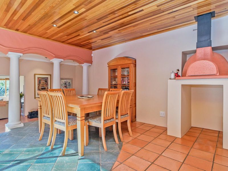 Dining area featuring a unique timber-clad ceiling, built-in pizza oven, and a combination of slate and terracotta tile flooring with decorative columns.