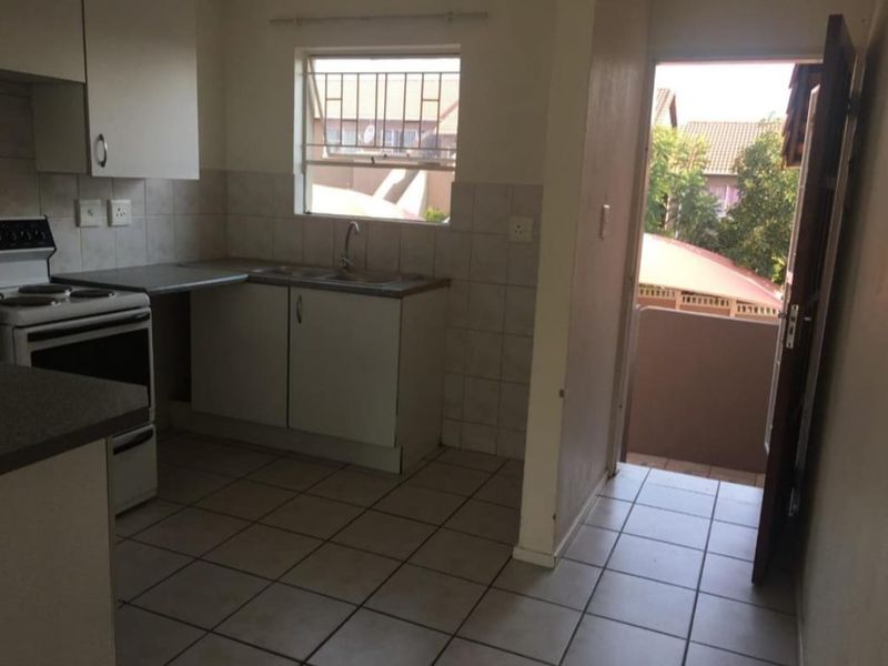 Functional kitchen featuring built-in cabinetry, tiled splashbacks, and a freestanding stove, with direct access to an exterior balcony area.