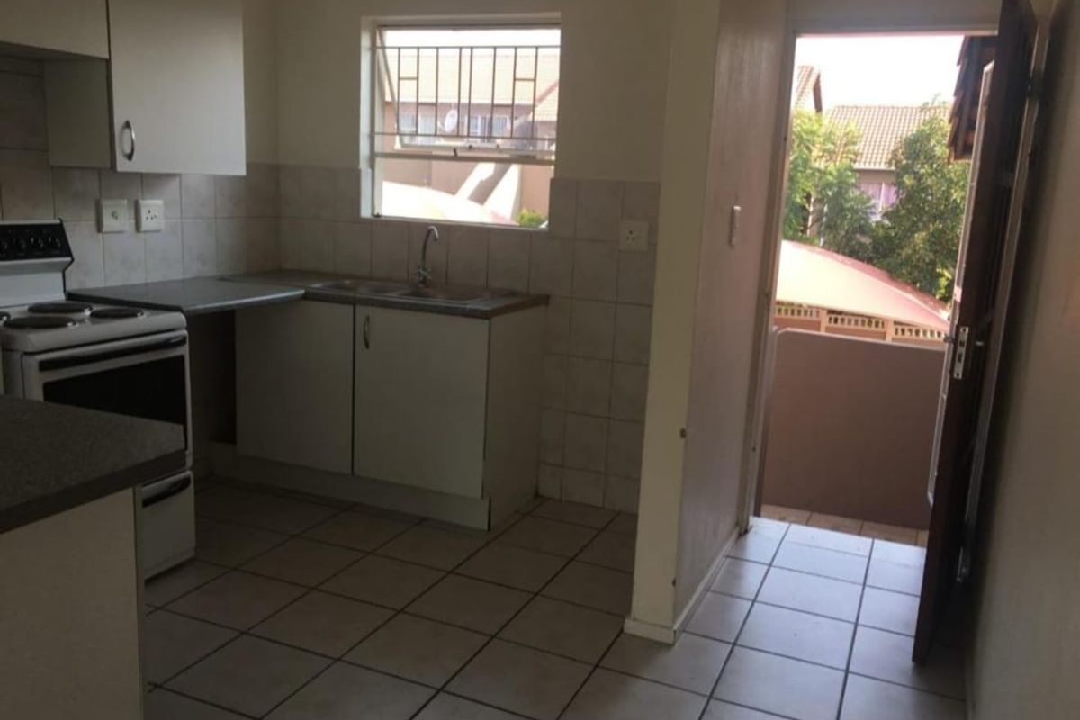 Functional kitchen featuring built-in cabinetry, tiled splashbacks, and a freestanding stove, with direct access to an exterior balcony area.