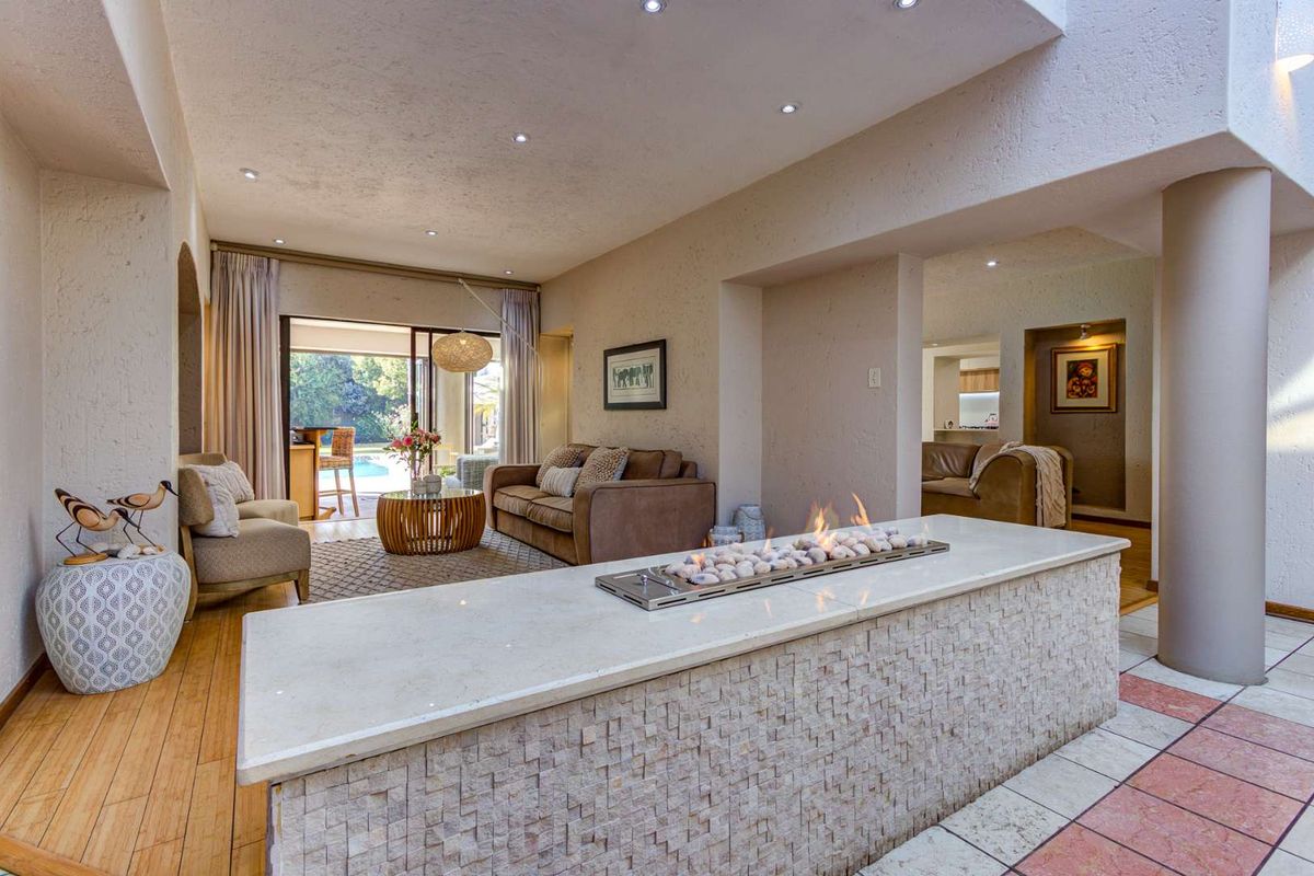 Spacious living area featuring a modern built-in gas fireplace with stone cladding, recessed lighting, and seamless access to the outdoor patio and pool area.