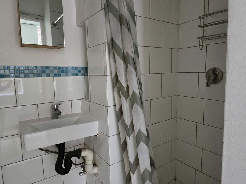 Compact bathroom featuring white subway wall tiling with a blue mosaic accent, a wall-mounted basin, and a shower enclosure.