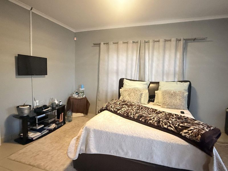 A standard bedroom featuring tiled flooring, neutral wall paint, and a curtain rod. The room includes visible surface-mounted electrical conduit.