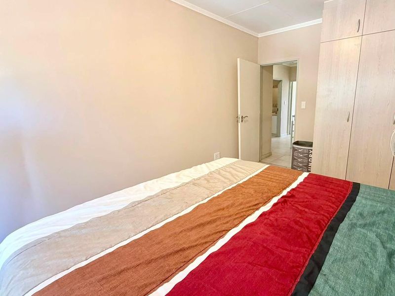 A bedroom featuring built-in cupboards and neutral wall finishes, with a doorway leading to an adjacent hallway.
